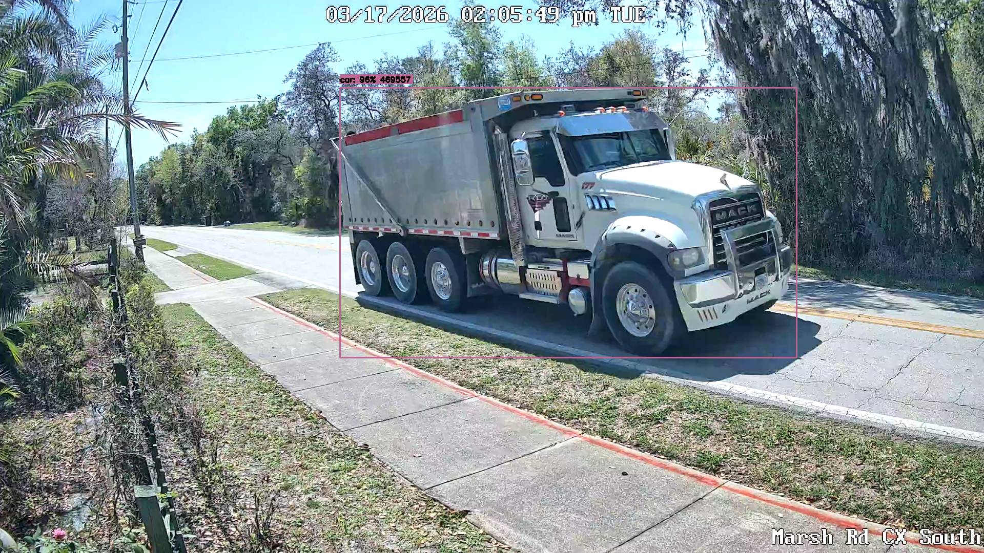 White Mack dump truck riding over yellow center line